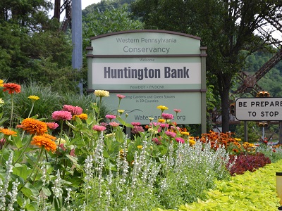 Colorful flowers bloom along the Parkway West approaching the Fort Pitt Tunnel. A sign recognizes Huntingdon Bank as the sponsor.