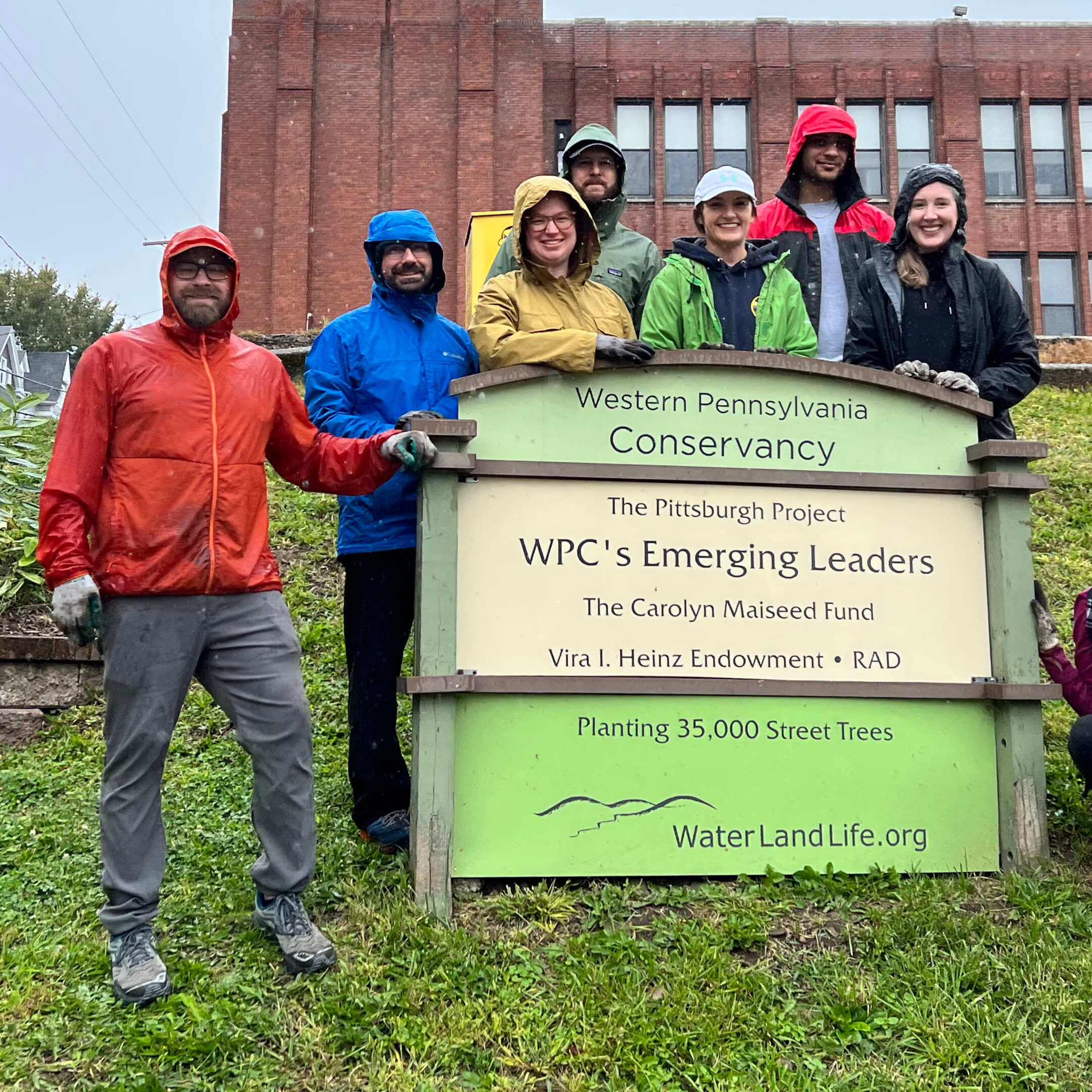 WPC Emerging Leaders pose with a garden sign during a garden pull-out event in the Fall of 2022.