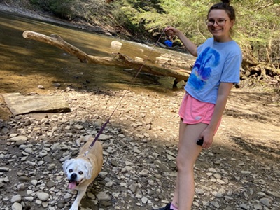 a person and a dog on a leash walk along the stream at Wolf Creek Narrows Natural Area